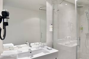 Ein modernes Badezimmer mit einer Glasdusche, einem Waschbecken und einem Spiegel im Sol Principe Hotel.