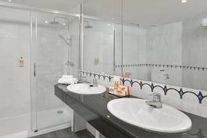 Das Badezimmer im Sol Principe Hotel mit einer Dusche, zwei Waschbecken und einem Spiegel.