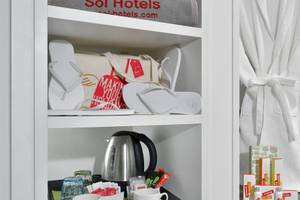 Ein Hotelzimmer des Sol Principe mit einem Schrank, Flip-Flops, einem Wasserkocher und weiteren Gegenständen.