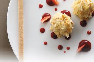 Mandel-Schoko-Kugel auf weissem Teller mit Erdbeeren und roter Glasur