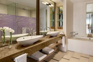 Ein modernes Badezimmer mit zwei Waschbecken, einer Badewanne und einem Spiegel im Shangri-La Le Touessrok Hotel.