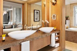 Badezimmer im Shangri-La Le Touessrok Hotel mit zwei Waschbecken, Badewanne und Fenster mit Palmbaumblick.