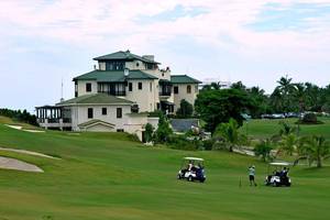 Golfplatz mit Golfwagen und Hotel Melia Las Americas im Hintergrund