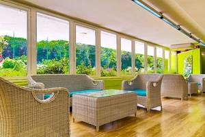 Loungebereich des VOI Alimini Resorts mit Rattanmöbeln und großen Fenstern.