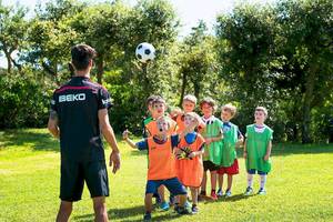 Kinder spielen Fußball im Freien mit einem Trainer auf dem VOI Alimini Resort