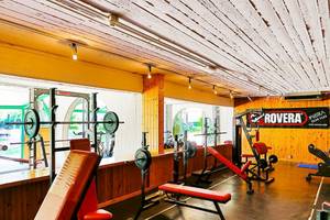 Fitnesscenter im VOI Alimini Resort mit verschiedenen Geräten und einer gelben Wand.