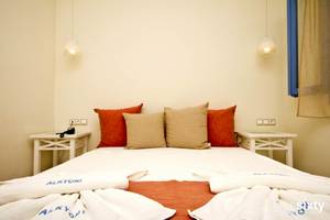 Ein Schlafzimmer im Alkyoni Beach Hotel mit zwei Nachttischen und zwei Lampen an der Wand.