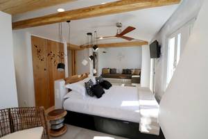 Schlafzimmer im Alkyoni Beach Hotel mit Doppelbett, weißen Wänden und Holzbalkendecke.