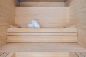 Innenansicht der Sauna im Hotel Iberostar Selection Sabila mit leeren Holzbänken und zwei weißen Handtüchern.