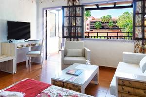 Innenansicht eines Hotelzimmers mit Schreibtisch, Fernseher, Bett, Sofa und Balkon mit Ausblick.