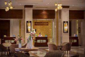 Reception Bereich von Sunrise Arabian Beach Resort mit Mann am Schalter und Blumenvasen.