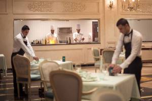 Servicepersonal im Restaurant des Sunrise Arabian Beach Resort, das Tische deckt.