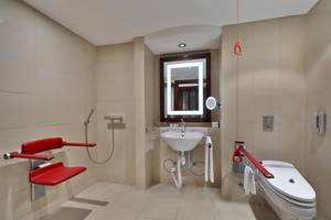 Barrierefreies Badezimmer im Sheraton Oman mit einer roten Sitzbank und einem behindertengerechten WC.