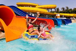 Zwei junge Frauen auf einer gelben und blauen Wasserrutsche im Pickalbatros Royal Moderna Resort.