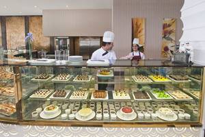 Patissier im Crystal Waterworld Resort & Spa serviert Kuchen in einem Glasschrank.