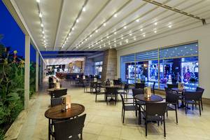 Außenbereich des Crystal Waterworld Aqua Collection Hotels mit beleuchteten Tischen und Stühlen.