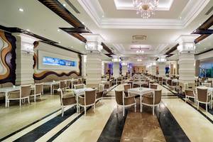 Innenbereich eines Restaurants im Crystal Waterworld Aqua Collection Hotel mit vielen Tischen und Stühlen.