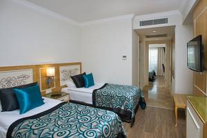 Zwei stilvolle Zimmer im Crystal Waterworld Aqua Collection Hotel mit Doppelbetten, Nachttischen und Fernsehern.