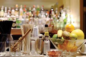 Cocktail-Zutaten auf einer Bar in einem Hotel, mit verschiedenen Früchten und Flaschen im Hintergrund.