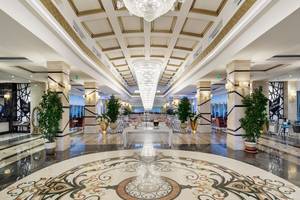 Hotellobby mit großen Kristallleuchten und einem kunstvollen Marmorbodendesign.