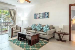 Wohnzimmer des Marien Puerto Plata Hotels mit grauem Sofa, Tisch und Dekor.