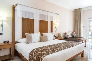 Hotelzimmer im Marien Puerto Plata mit Bett, Nachttisch, Sofa und Fenstern.