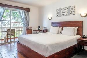 Marien Puerto Plata Hotel Schlafzimmer mit Bett, Fenstern und Balkon.