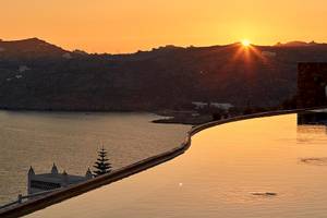 Sonnenuntergang am Pool der Myconian Villa Collection mit Blick auf das Meer und die Berge.