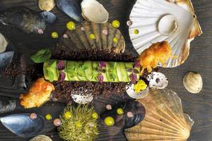 Kulinarisches Arrangement des Myconian Villa Collection mit Meeresfrüchten und grünem Gemüse