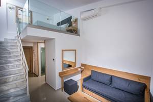 Innenbereich des Gouves Water Park Holiday Resort mit gefliester Treppe, Glasbalkon und einem Bett im oberen Stockwerk.
