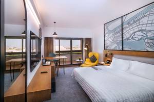 Innenansicht eines Hotelzimmers im Le Meridien Abu Dhabi mit Bett, Schreibtisch und Stadtblick.
