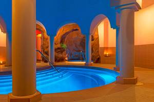 Innenpool im Le Meridien Abu Dhabi Hotel mit blau beleuchtetem Wasser und Säulen.