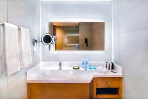 Badezimmer im Le Meridien Abu Dhabi mit Spiegel, Waschbecken und Toilettenartikeln.