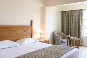 Schlafzimmer im Mitsis Petit Palais Beach Hotel mit Bett, Lampe und Fenster