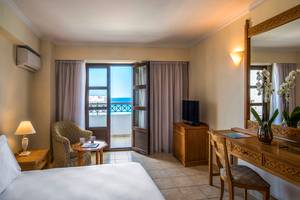 Innenansicht eines Zimmers im Mitsis Petit Palais Beach Hotel mit Meerblick.