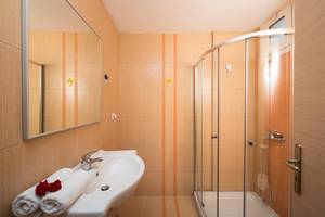 Badezimmer im Gouves Water Park Holiday Resort mit einer Dusche, einem Waschbecken und Handtüchern.