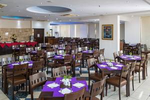 Innenansicht des Restaurants im Gouves Water Park Holiday Resort mit gedeckten Tischen und Stühlen.