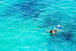Person schnorchelt im kristallklaren Wasser vor dem InterContinental Resort Mauritius