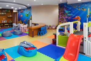 Kinderspielzimmer im Dukes The Palm, a Royal Hideaway Hotel mit bunten Teppichen, Spielsachen und einem blauen Wandbild.