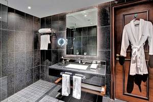 Badezimmer im Dukes The Palm, einem Royal Hideaway Hotel mit schwarzen Kacheln, einer Glasdusche und einem Waschbecken.