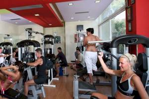Fitnessstudio im Cathrin Hotel mit verschiedenen Geräten und trainierenden Personen.