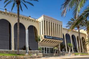 Außenansicht des Barcelo Corralejo Bay Hotels mit Palmen und bogenförmigen Fenstern.