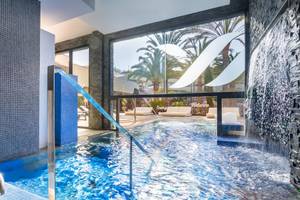 Innenpool im Barcelo Corralejo Bay Hotel mit blauen Fliesen und Wasserfall.