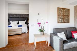 Innenansicht eines Zimmers im Barcelo Corralejo Bay Hotel mit Bett, Sofa, Tisch und Kunstwerk an der Wand.