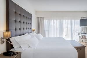 Hotelzimmer im Barcelo Corralejo Bay mit einem großen Bett, einem Schreibtisch und einem Fernseher an der Wand.