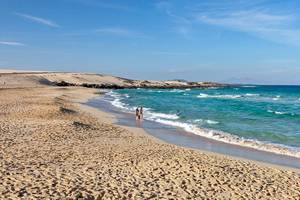 Strand des Barcelo Corralejo Bay Hotels mit kristallklarem Wasser und zwei Personen im Wasser