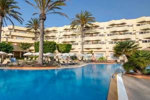 Außenbereich des Barcelo Corralejo Bay Hotels mit Swimmingpool, Sonnenliegen und Palmen