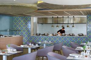 Restaurant im Atlantica Imperial Resort & Spa mit bunten Wandfliesen und einer Person, die hinter der Theke steht.
