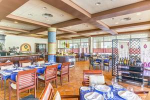 Innenansicht des Restaurants im Royalton Hicacos Resort & Spa mit blauen Tischdecken und Holzstühlen.