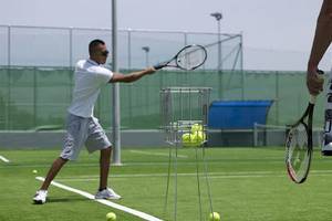 Tennisspieler im Training auf dem Platz, Tennisschläger haltend und auf einen Ball schlagend.